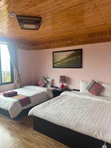a bedroom with two beds and a wooden ceiling at Nhà Nghỉ Đức Anh in Sa Pa