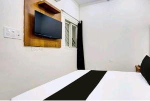 Un dormitorio con una cama con un televisor de pantalla plana en la pared. en Hotel Himalaya, en Kota