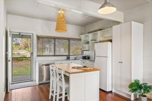 Una cocina con gabinetes blancos y un refrigerador blanco. en Werri Beach Shack, en Gerringong