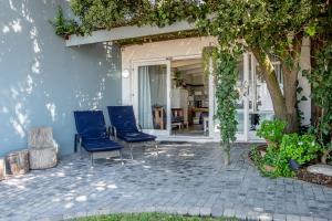 a patio with two blue chairs and a tree at Piccolo Villa in St. Helena Bay