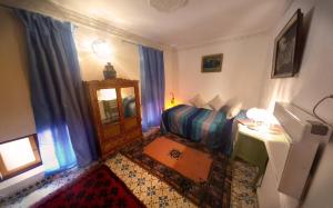 a bedroom with a bed and a desk and a window at Riad Atika Mek in Meknès