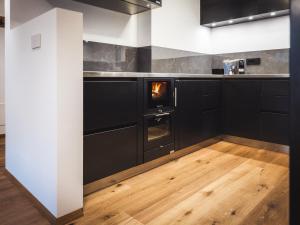 a kitchen with black cabinets and a fire in the oven at Paradeis Apartments A19 in Mühlbach +15 photos