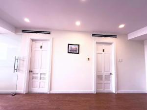 two white doors in a white room with wood floors at Phoenix Hotel Vung Tau in Vung Tau