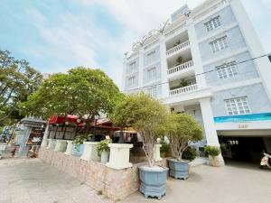 a large white building with trees in front of it at Phoenix Hotel Vung Tau in Vung Tau