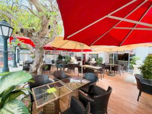 a patio with tables and chairs with a red umbrella at Phoenix Hotel Vung Tau in Vung Tau
