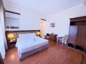 a bedroom with a large white bed and wooden floors at Phoenix Hotel Vung Tau in Vung Tau