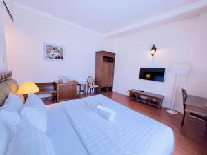 a bedroom with a white bed and a living room at Phoenix Hotel Vung Tau in Vung Tau