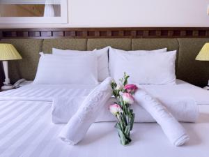 a white bed with a vase of flowers on it at Phoenix Hotel Vung Tau in Vung Tau