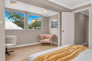 ein Schlafzimmer mit einem Bett und einem Stuhl und Fenstern in der Unterkunft 'Parkstone' Modern Elegance near CBD & Zoo in North Adelaide
