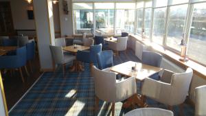 un restaurante con mesas, sillas y ventanas en Park Hotel en Thurso