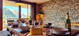 a wooden table with wine glasses and wine bottles at Les Flambeaux - Apartment with Panoramic View - Alp'in C in Châtel