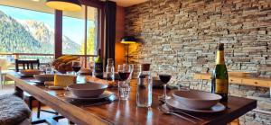 a wooden table with glasses and a bottle of wine at Les Flambeaux - Apartment with Panoramic View - Alp'in C in Châtel
