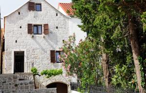 a white stone house with trees in front of it at Villa Urska in Bol