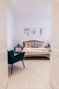 a bedroom with a bed and a green chair at Brand New! Valletta Boutique Style Apartment in Valletta