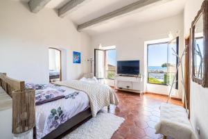 a bedroom with a bed and a tv and windows at Villa Flore - Panoramic Sea View by Halldis in Vallauris