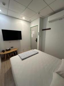 a bedroom with a white bed and a flat screen tv at Shuang Shuang in Tainan