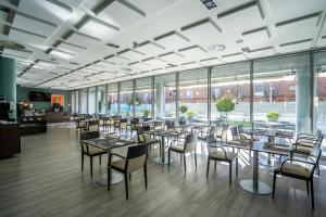 a dining room with tables and chairs and windows at Abba Huesca in Huesca