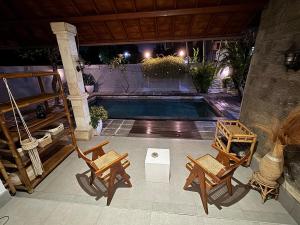 a patio with chairs and a swimming pool at night at Balieys Villa, Tranquil Hideaway in Central Canggu in Canggu