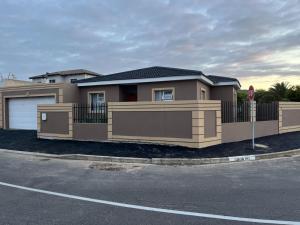 a brown house with a gate and a stop sign at West Coast comfortable stays in Cape Town