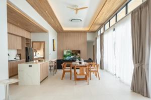 eine Küche und ein Esszimmer mit Tisch und Stühlen in der Unterkunft Mouana Breeze Maikhao 3-bedroom Pool Villa in Mai Khao Beach
