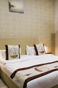un letto con lenzuola e cuscini bianchi in una stanza di AL MARSA HOTEL APARTMENTS a Khor Fakkan Altre 37 foto