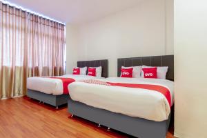 two beds in a bedroom with red and white pillows at Dancenter Medan City Near Medan Station MDN in Medan