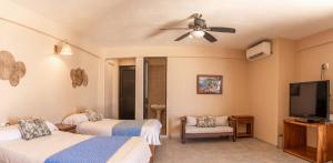 a hotel room with two beds and a flat screen tv at Hotel El Mirador in Puerto Escondido
