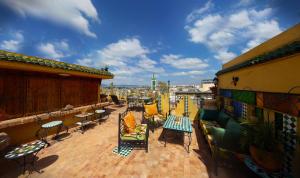 Un balcón con sillas y mesas en un edificio. en Riad Atika Mek, en Meknès