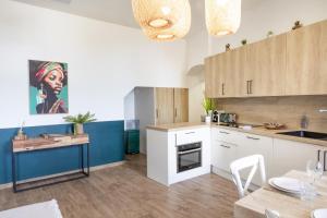 a kitchen with white cabinets and a blue wall at Les Logettes 2 in Menton