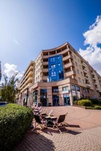 budynek z krzesłami i stołami przed nim w obiekcie Green Kabaty Apartment 1 w Warszawie