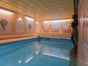 a swimming pool with a woman standing next to it at Residence Rastbichl - Apartments & Indoor-Pool in Maranza