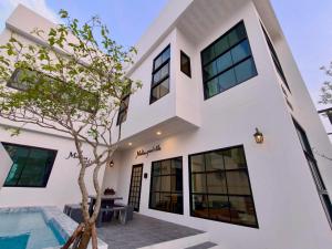 a white house with a swimming pool and a tree at Medina Private Pool Villa-บางแสน in Ban Puk (1)