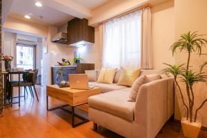a living room with a couch and a table with a laptop at Residence Hotel Ryogoku in Tokyo