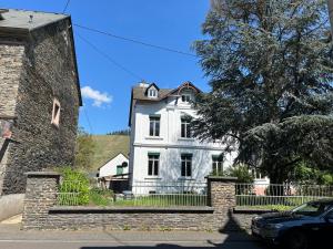 Winzervilla Kammerhof - 3x stilvolle & geräumige FeWos mit Moselblick, 2-12 Gäste buchbar, direkt am Moselradweg في برونبيبيرغ: بيت أبيض مع سيارة متوقفة أمامه