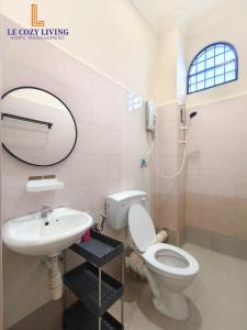 a bathroom with a toilet and a sink and a mirror at The Cozy Retreat House at Bukit Mertajam in Bukit Mertajam