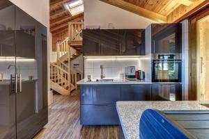 a large kitchen with blue cabinets and a staircase at Chalet Khione in La Tzoumaz