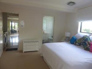 a white bedroom with a bed and a bathroom at Chez Jacques in Coffs Harbour +14 photos