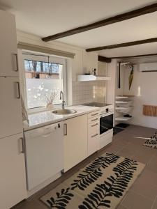 Una cocina con gabinetes blancos y un fregadero y una ventana. en 1st Class Escape, en Kågeröd