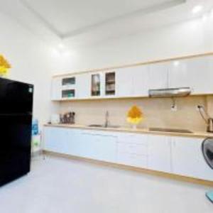 una cucina con mobili bianchi e un frigorifero nero di Villa Thai Anh a Ấp Chợ Dinh