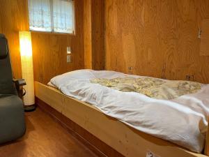 an unmade bed in a room with a wooden wall at Guesthouse Otaru Wanokaze single room / Vacation STAY 32196 in Otaru