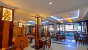 a restaurant with wooden tables and chairs and windows at Champlung Mas Hotel Legian in Legian