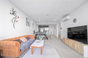 a living room with a couch and a tv at Scenic Skyline view2BR APT close to OlympicPark in Sydney