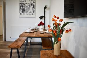 a wooden table with a vase with orange flowers in it at Breathtaking Camberwell Skyline Views in London