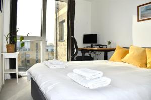 a bedroom with a white bed with towels on it at Breathtaking Camberwell Skyline Views in London