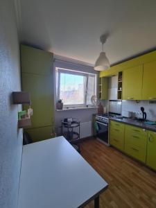 a kitchen with yellow cabinets and a table in it at Istabiņa Carnikavā in Carnikava