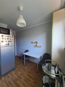 a kitchen with a white table and a refrigerator at Istabiņa Carnikavā in Carnikava