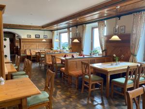 a restaurant with wooden tables and chairs and windows at Berggasthof Ferienhaus Gut Lichtenau in Hauzenberg