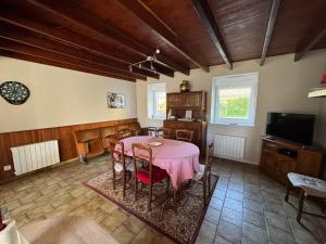 a dining room with a table and a tv at Chez Ferdi à la campagne in Sortosville-en-Beaumont