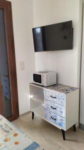 - un four micro-ondes sur une commode avec une télévision murale dans l'établissement Casa Vacanze STELLA MARINA, à Torre San Giovanni