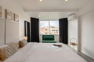 カスカイスにあるBreeze Apartment by Olala Homesの緑の椅子が備わる客室の大きな白いベッド1台